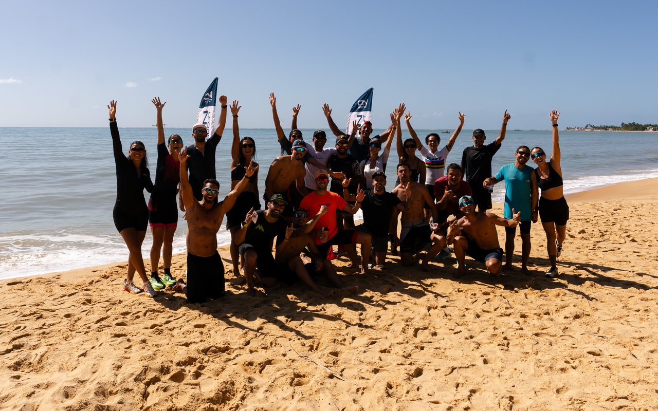 Galera do simulado reunida na praia, de braços erguidos
