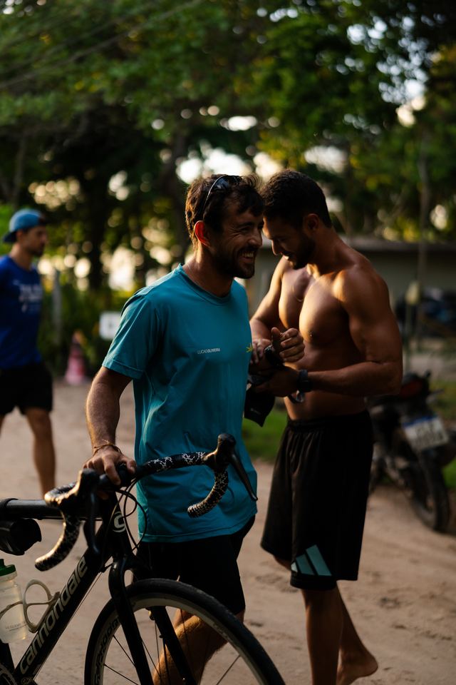Atletas sorrindo com a bike na chegada
