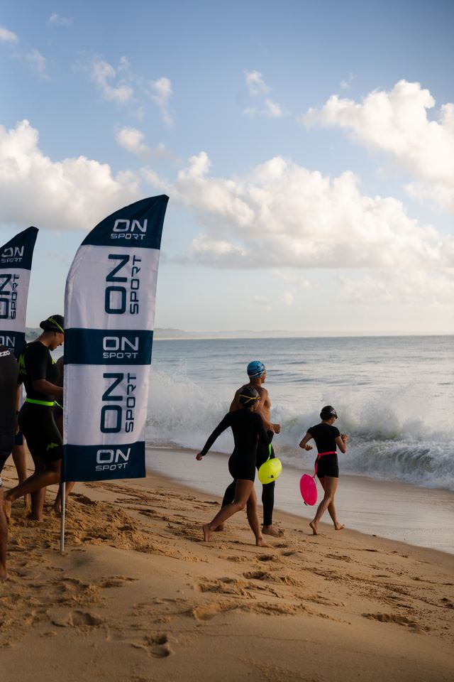 Nadadores indo para o mar ao lado das bandeiras