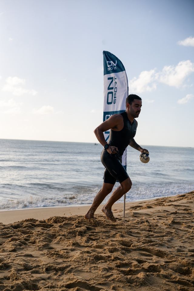 Atleta correndo na areia ao sair da água