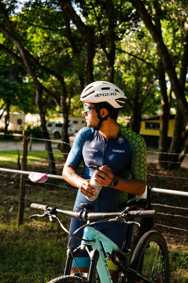 Atleta na área de transição, de capacete e kit de ciclismo