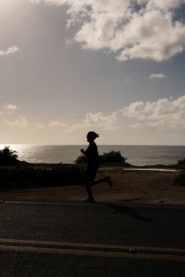 Corredora em silhueta com o mar ao fundo