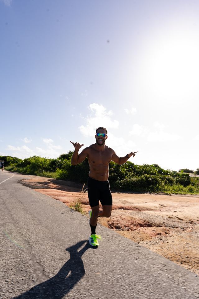 Atleta correndo e fazendo o sinal de hang loose