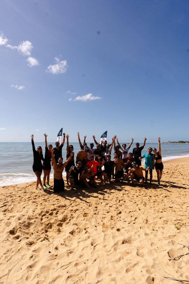 Galera do simulado reunida na praia, de braços erguidos